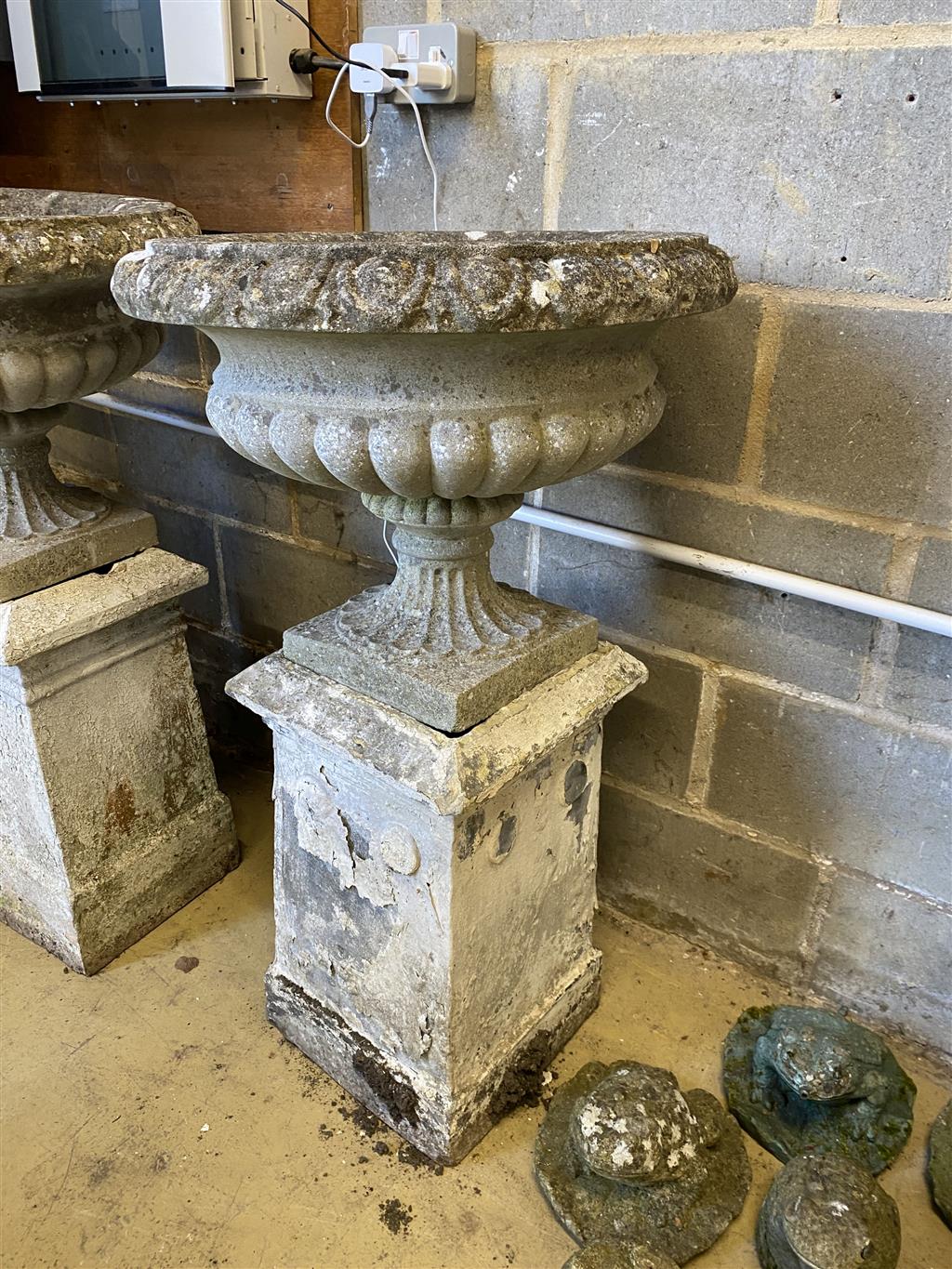 A pair of reconstituted stone campana garden urns and pedestals, 56cm diameter, height 99cm